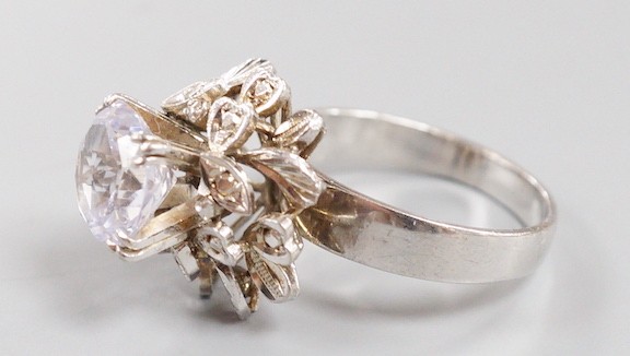 A modern white metal (tests as 18ct) and solitaire white sapphire set flower head ring, in a raised setting, size S/T, gross weight 8.1 grams.